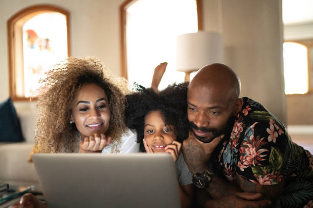 familia feliz viendo película en un ordenador portátil - lying down women laptop freedom fotografías e imágenes de stock