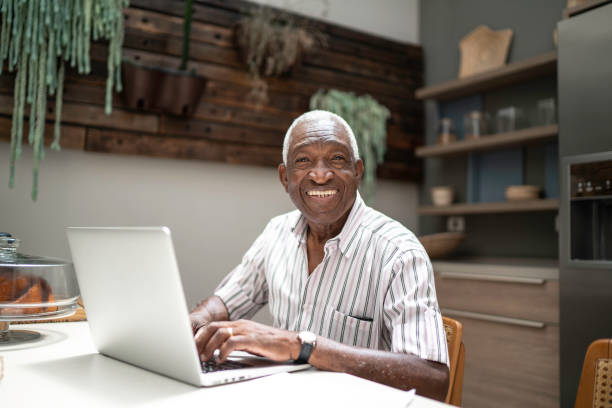 istock Portrait of a senior man using laptop in the kitchen table 1182452113