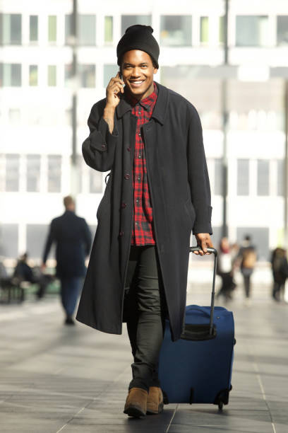homme de voyage d'afro-américain de pleine longueur frais marchant dans la station avec le téléphone portable et le sac - pulling a name from a hat photos et images de collection