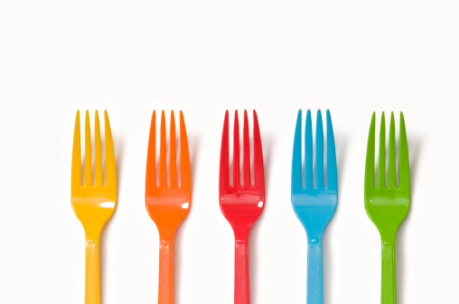 Five colorful plastic forks in a row shot on a white background.