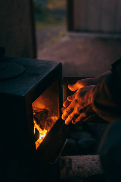 istock Older man warms his hands by the stove 1182453422