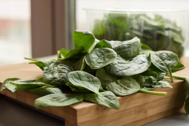 Baby spinach leaf on the kitchen wooden board Baby spinach leaf on the kitchen wooden board spinazie stock pictures, royalty-free photos & images