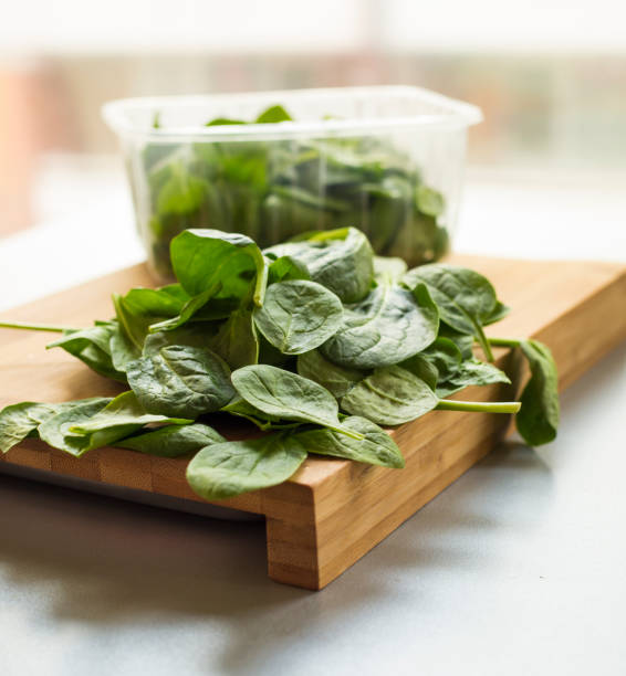 Baby spinach leaf on the kitchen wooden board Baby spinach leaf on the kitchen wooden board spinazie stock pictures, royalty-free photos & images