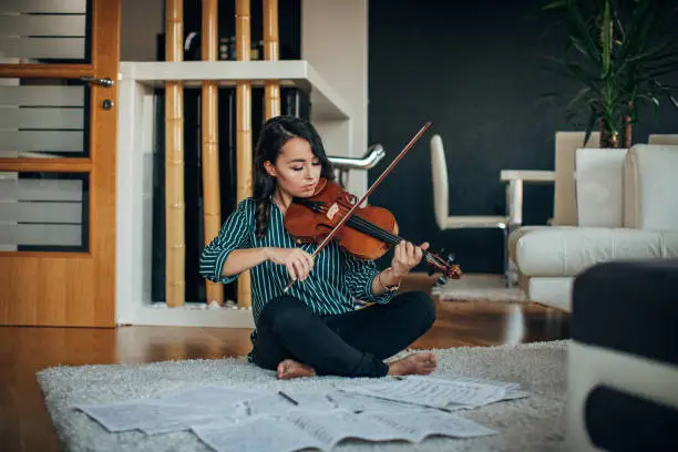 Young woman violinist practicing at home