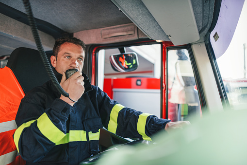 Professional firefighter talking on the radio station before leaving the fire station