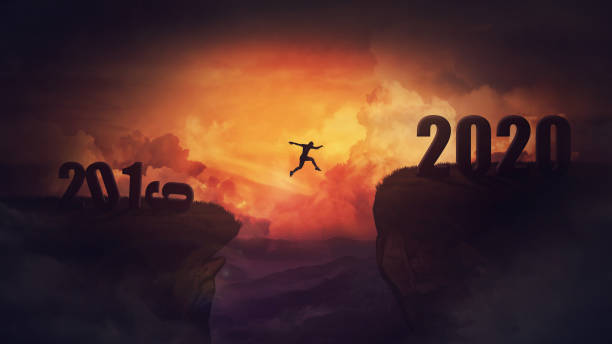 istock Surreal scene, man jump over a chasm obstacle between 2019 and 2020 years. Self overcome, starting a new year. Way to win and success, sunset sky background. Motivational achieving goals concept. 1182456792