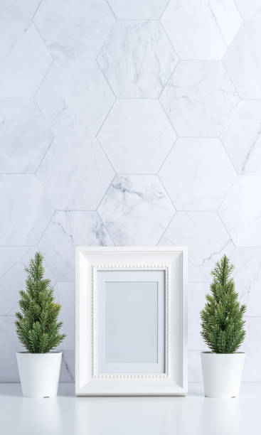 istock white vintage photo frame with christmas tree,pine cone and decor xmas ball on white table and marble tile wall background.clean minimal simple style.holiday still life mockup to display design 1182457413