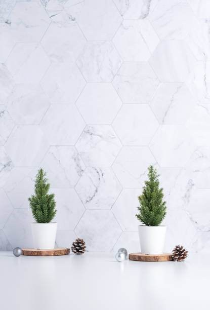 istock christmas tree with pine cone,decor xmas ball on wood log at white table and marble tile wall background.clean minimal simple style.holiday still life with space to adding text 1182457445