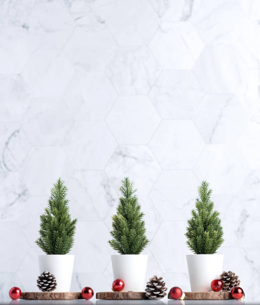 istock Three christmas tree with pine cone and decor xmas ball on white table and marble tile wall background.clean minimal simple style.holiday still life mockup banner with space to adding text 1182457496