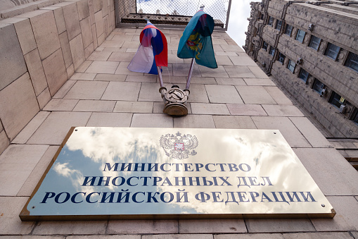 Russia Moscow 2019-06-17 Gold shiny signboard of Ministry of Foreign Affairs with Russian flag, flag of MID of Russia and inscription plate on Russian. One of seven stalinism skyscrapers