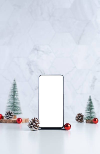 mockup screen mobile with Christmas tree with pine cone and decor xmas ball on white table and marble tile wall background.clean minimal simple style.holiday still life template for advertise online