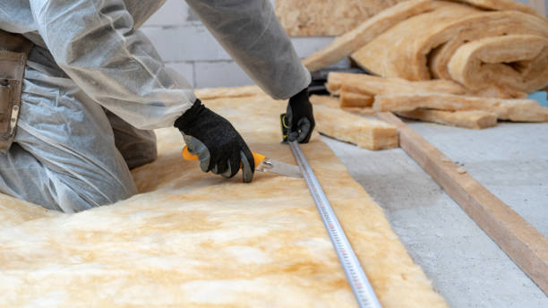 Professional workman installing thermal insulation rock wool under the roof Cropped view of professional workman in protective workwear using knife and holding measuring tape over material, installing thermal insulation rock wool under the roof remote location stock pictures, royalty-free photos & images