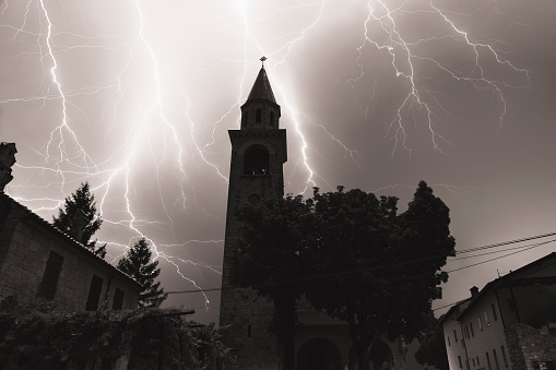Black and white photo of lightning over church tower in village Temnica (Karst - Slovenia)
