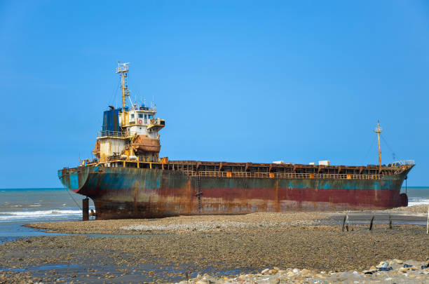 Cargo ship run aground on rocky  shore waiting for rescue.