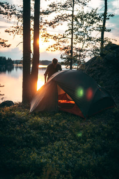 Man is standing next to the tent standing in the forest