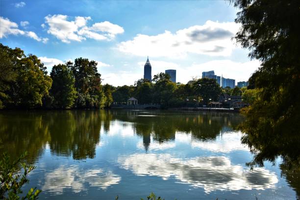 istock Trees and blue sky with clouds reflecting on lake 1182463098