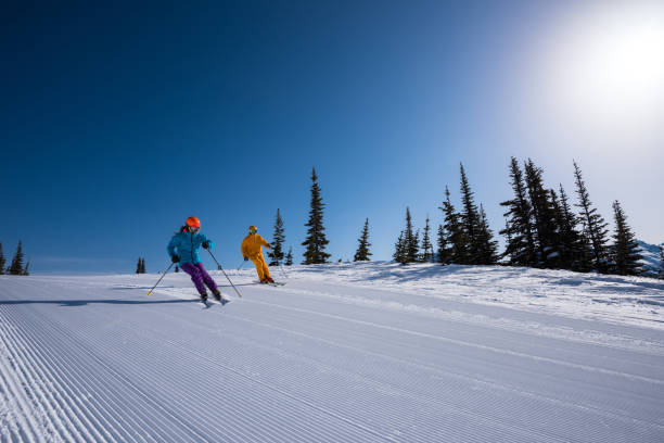 Couple skiing groomed runs on a sunny day. Winter vacations. Skiing Whistler, Canada.