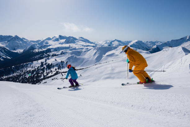 Couple enjoying a ski vacation Couple skiing groomed runs on a sunny day. Winter vacations. Skiing Whistler, Canada. whistler skiing stock pictures, royalty-free photos & images