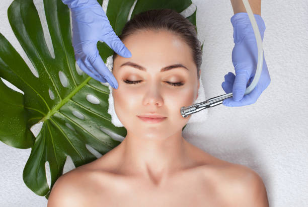 美容師は美容院で女性の顔の皮膚のマイクロダーマブレーション手順を行います。美容とプロのスキンケア。 - マイクロピーリング ストックフォトと画像