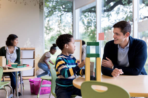 istock Young boy shows teacher what he is building 1182464385