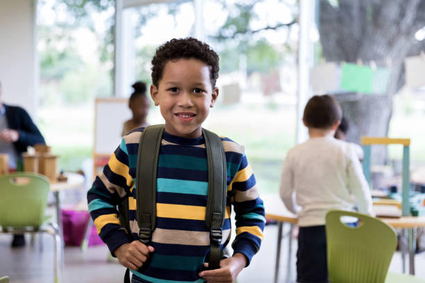 istock Young boy in bright striped shirt wears backpack 1182464388