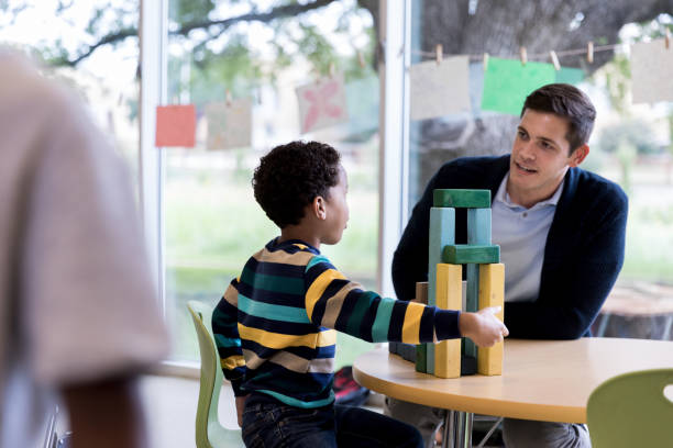 istock Young boy and teacher sit at table and talk together 1182464391