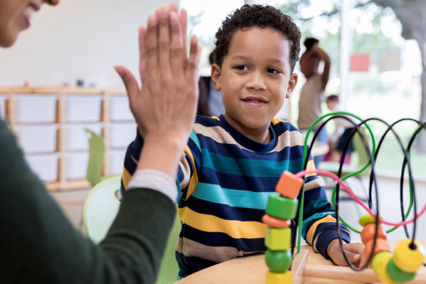 istock Child and teacher share high five after solving bead puzzle 1182464403