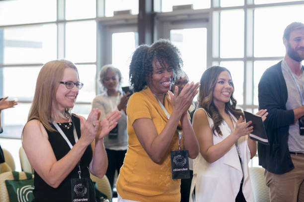istock Women smiling cheerfully while applauding conference speaker 1182464455