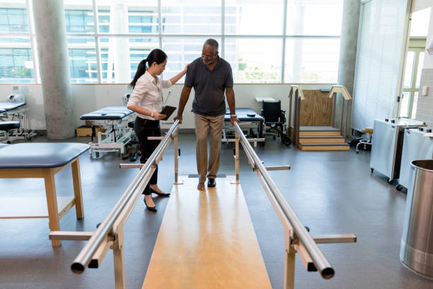istock Physical therapist helps mature man take first steps after surgery 1182464758