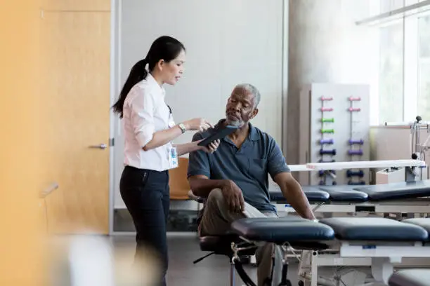 Photo of Female doctor talks with senior male patient