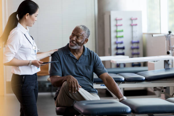 confident female doctor visits with senior patient - examination table imagens e fotografias de stock