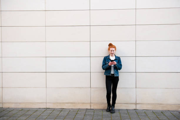 istock While waiting, young woman text messages friends 1182465026