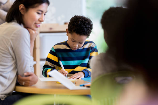 istock Caring teacher helps kindergarten students 1182465187