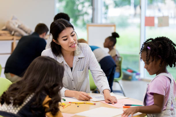 istock Helpful kindergarten teacher helps little girl 1182465191