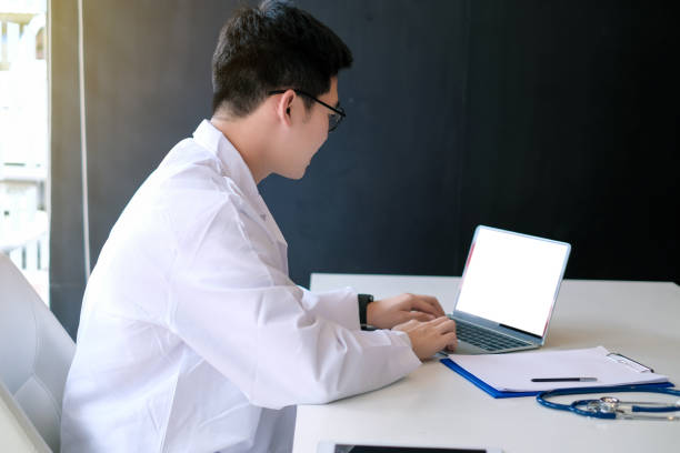 istock Mock up. Doctor working with laptop computer and see patient record in document. 1182467711