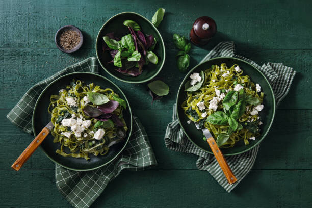 Vegan Gluten-Free Creamy Spinach Pasta Vegan Gluten-Free Creamy Spinach Pasta and vegan cheese on dark green background basil photos stock pictures, royalty-free photos & images