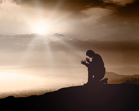 Prayer kneeling and praying to God on mountain autumn sunset background