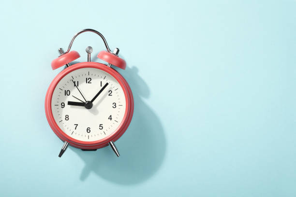 istock Red alarm clock with shadow lying on blue background. View from above. 1182469558