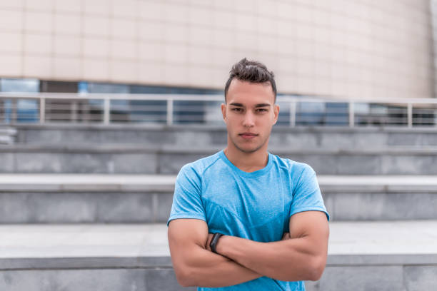 istock Male athlete posing confidently looking, coach summer day city, building background. Active youth lifestyle, fitness workout nature. Free space for text strength and motivation. 1182469801
