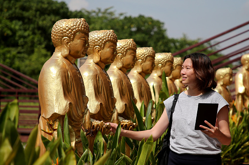 A female adult is enjoying sightseeing and admiration golden Buddha statues at Chinese temple in Ipoh, Perak Malaysia.