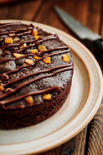 Chocolate and Orange Cake on a rustic plate on a dark wood table.