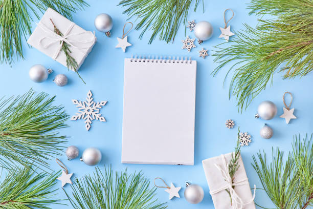 istock Mockup white notebook with snowflakes, pine branches  and gift box on a blue background 1182475288