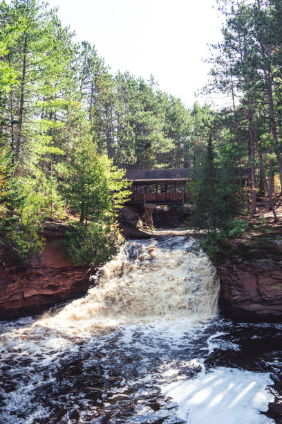 istock Amnicon Falls State Park waterfall with a covered bridge, over the Amnicon River in Northern Wisconsin 1182476504