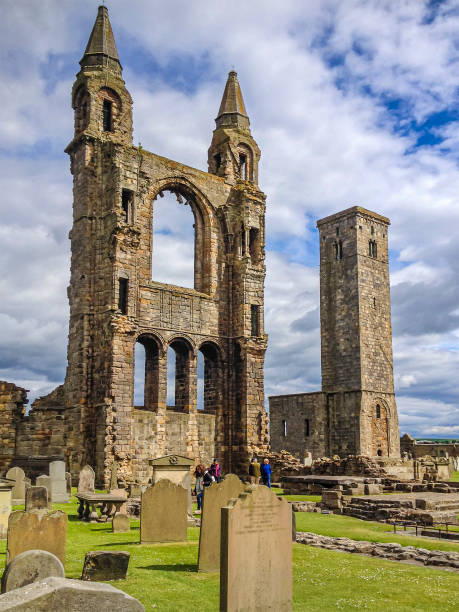 Tourists visiting the grounds of the St Andrews Cathedral, a ruined Roman Catholic cathedral located to the east of the town centre in St Andrews, Fife, Scotland. It was built in 1158 and at time it was the largest church to have been built in Scotland. Next to the cathedral ruins stands the even older St Rule's tower, that is said to date from around 1120 and 1150.