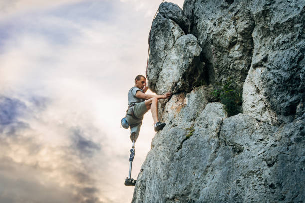 Disability man free rock climbing Man with prosthetic leg free mountain climbing prosthetic equipment photos stock pictures, royalty-free photos & images