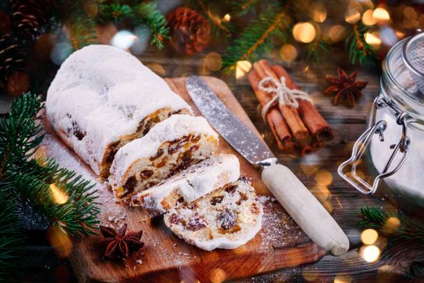 bolo de fruta tradicional de stollen do natal no fundo de madeira com luzes de natal - christmas stollen christmas pastry baked - fotografias e filmes do acervo