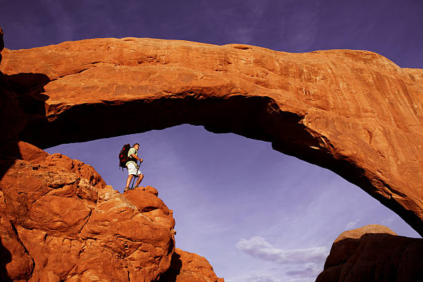 istock Backpacker On High Rocky Ledge Under Magnificent Stone Arch 118248753
