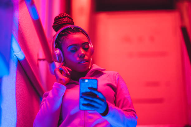 portrait of young black woman listening to music under neon lights - red hair hairstyle dyed hair women imagens e fotografias de stock