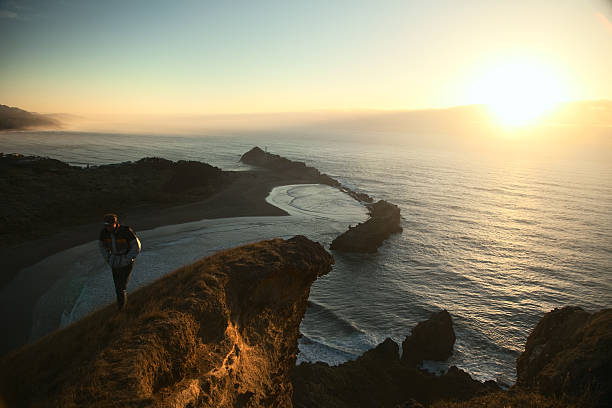 hombre en rocky coast, luz de la mañana - castlepoint fotografías e imágenes de stock