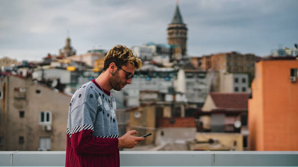 istock blond man using his phone in front of galata tower 1182488462